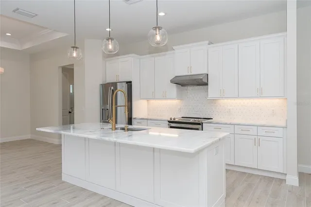 a kitchen with stainless steel appliances granite countertop white cabinets and a refrigerator