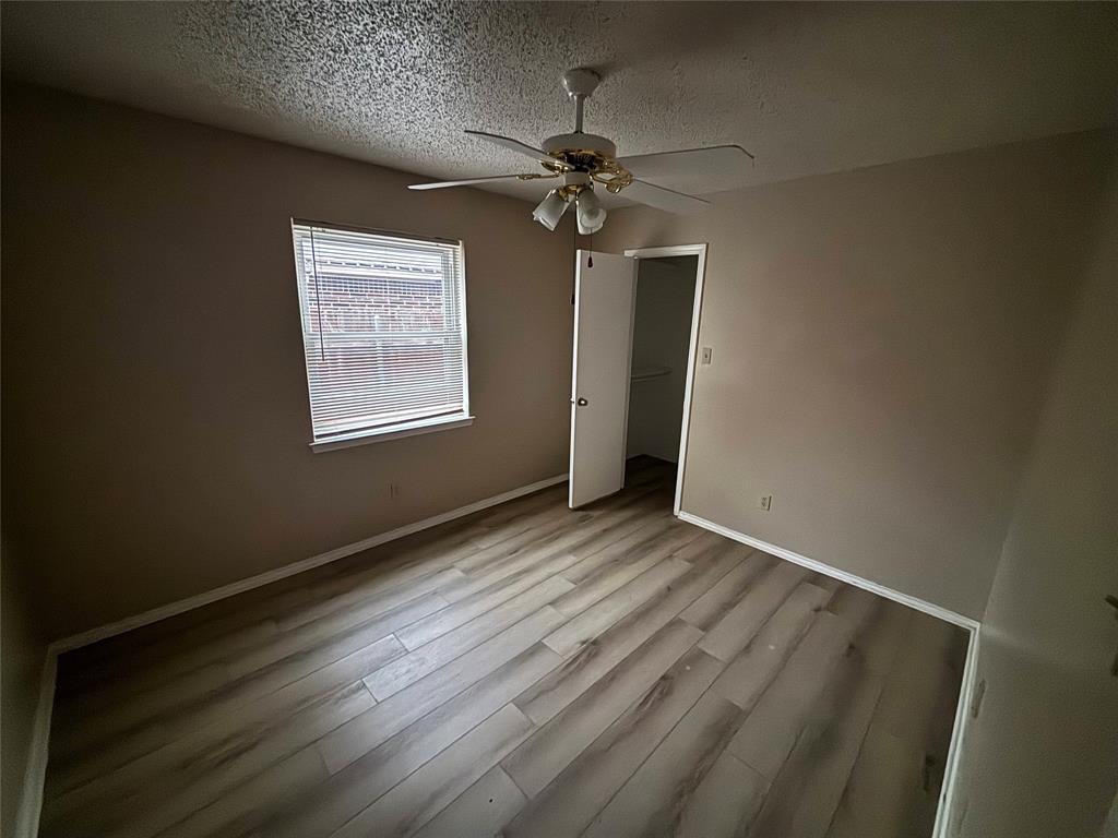 5916 Birchhill Road Watauga, TX 76148 - Photo 8 of 12 an empty room with wooden floor chandelier fan and windows