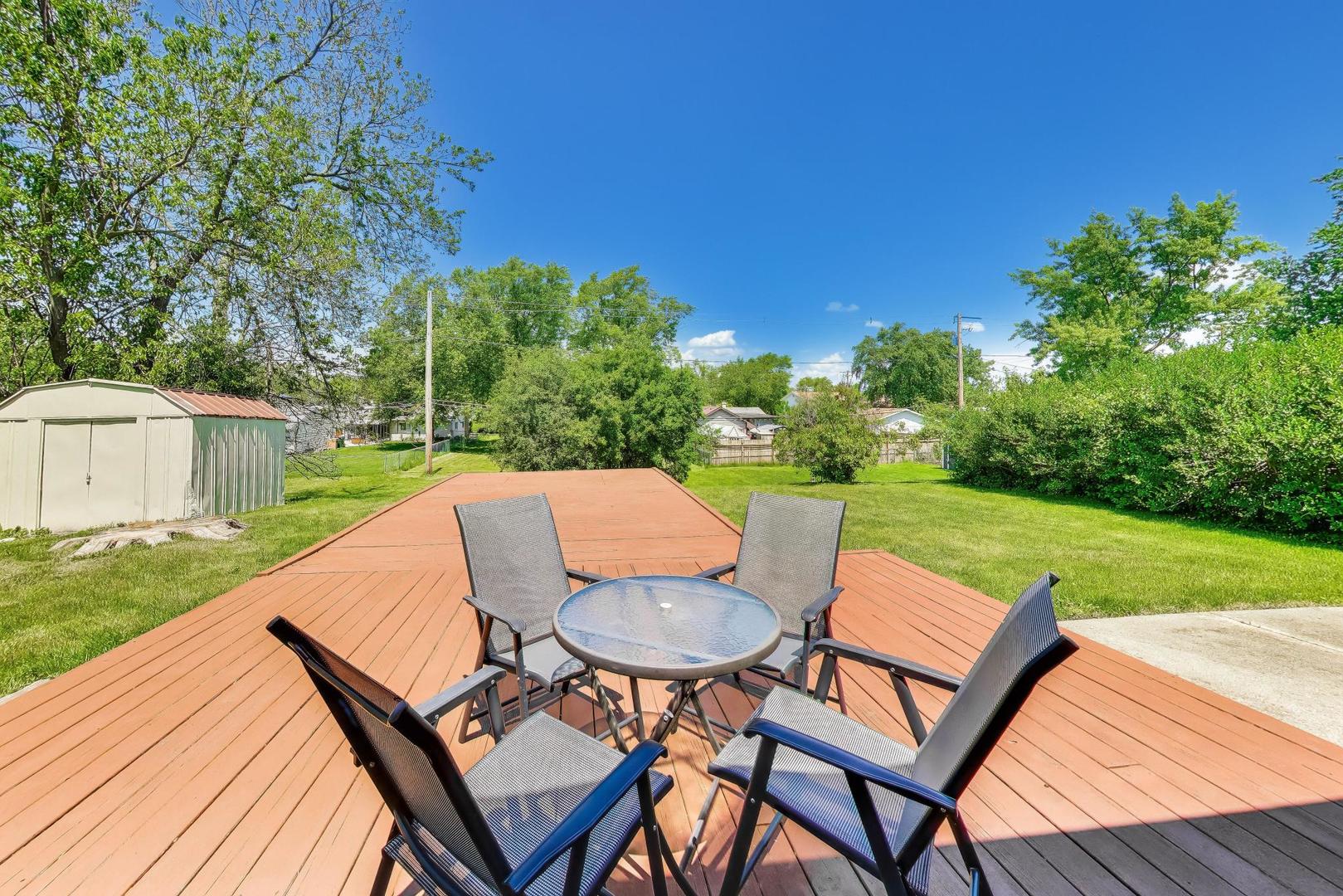 420 Bode Road Hoffman Estates, IL 60169 - Photo 15 of 20 a view of a patio with table and chairs under an umbrella with wooden floor and fence