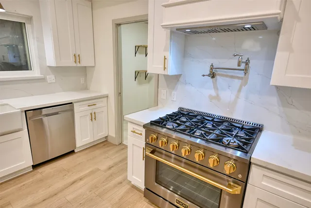a kitchen with white cabinets and appliances