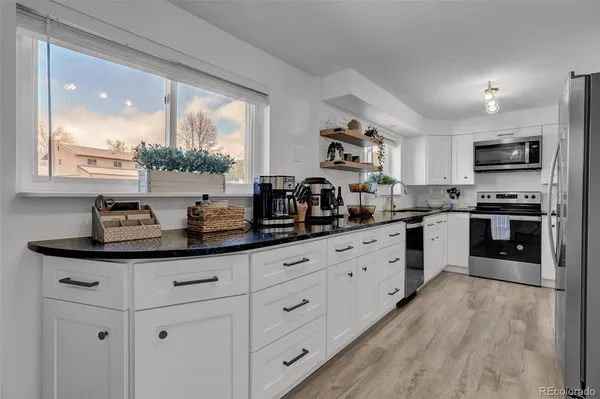 a kitchen with kitchen island granite countertop a sink a counter space appliances and cabinets