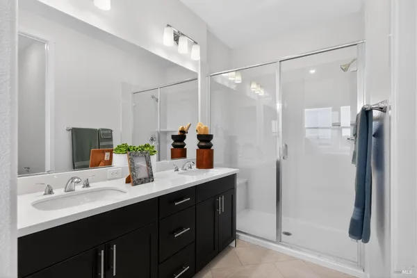 a bathroom with a double vanity sink mirror and shower