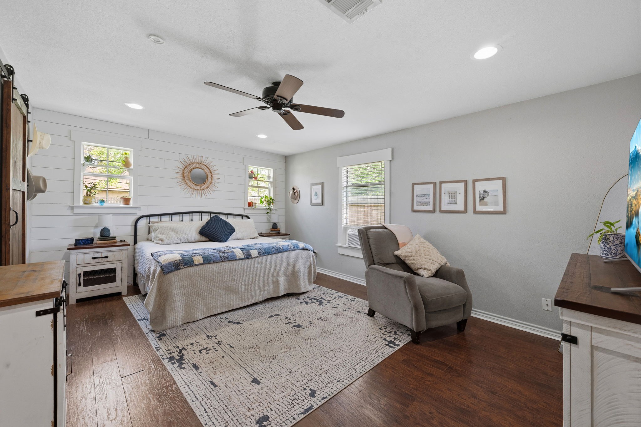 431 Corydon Drive Houston, TX 77336 - Photo 15 of 26 Bright and inviting primary bedroom showcasing rich laminate wood floors, a stylish shiplap accent wall, and abundant natural light from multiple windows, creating a peaceful retreat.