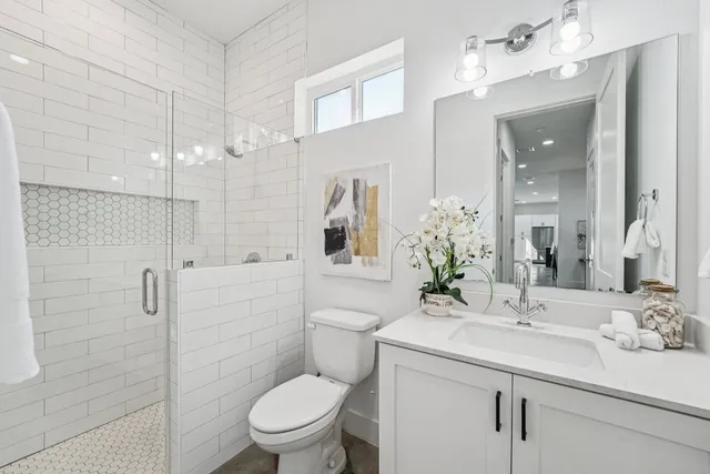 a bathroom with a toilet a sink a mirror a vanity and shower
