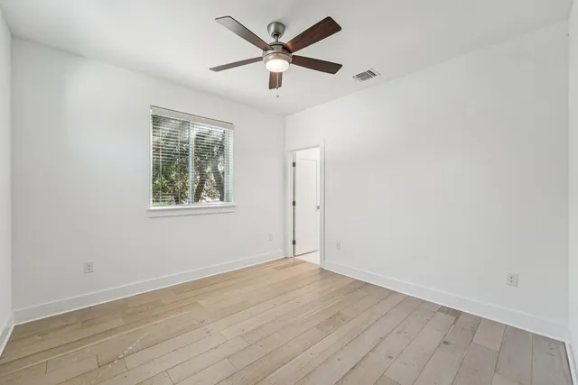 an empty room with wooden floor and ceiling fan