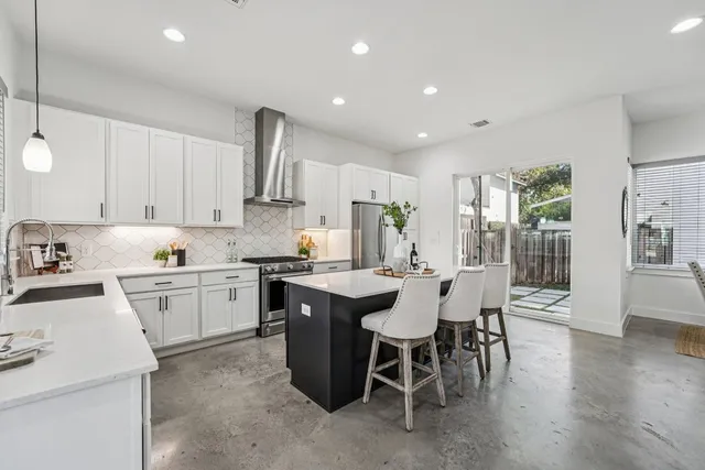a kitchen with a dining table chairs wooden floor cabinets and appliances