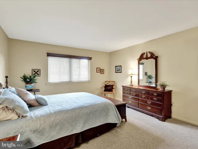 a bedroom with a bed and a dresser next to a window