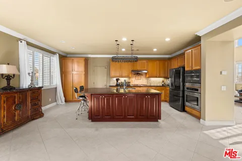 a open kitchen with stainless steel appliances kitchen island granite countertop a refrigerator and wooden cabinets