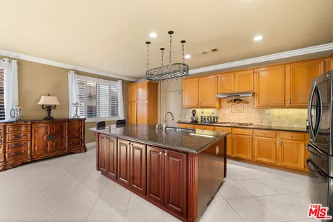 a large kitchen with kitchen island granite countertop a large counter top space appliances and a large window