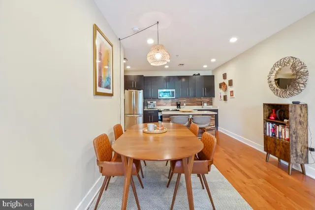a kitchen with stainless steel appliances granite countertop a dining table chairs and a refrigerator