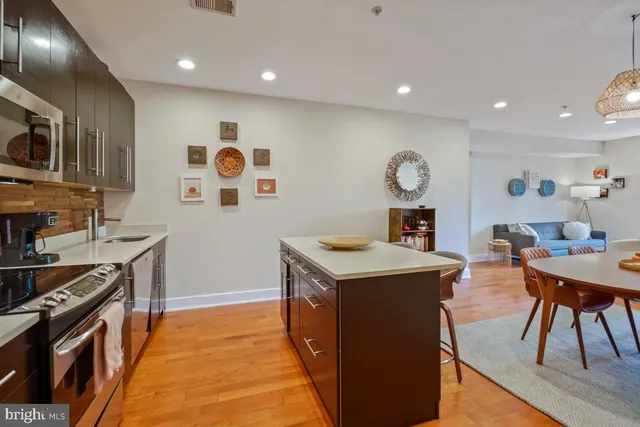 a kitchen with stainless steel appliances granite countertop a stove a sink dishwasher and a dining table with wooden floor