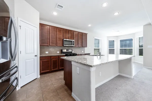 a kitchen with stainless steel appliances granite countertop a stove top oven a sink and a refrigerator