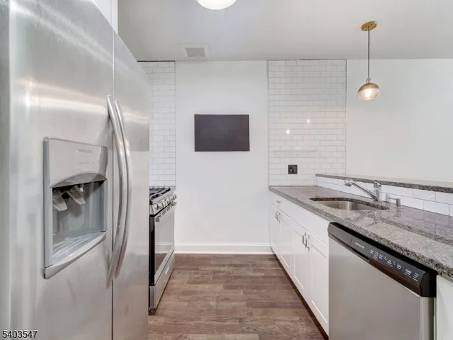 a kitchen with stainless steel appliances granite countertop a sink and a refrigerator
