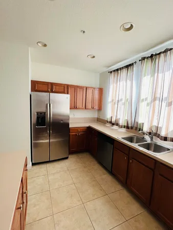 a large kitchen with granite countertop a refrigerator and a sink