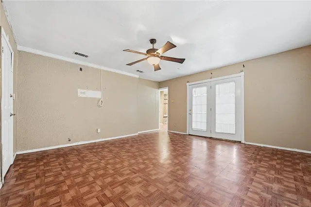 a view of an empty room with chandelier fan and wooden floor