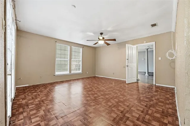 a view of an empty room with window and chandelier fan