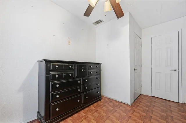 an empty room with wooden floor fan and windows
