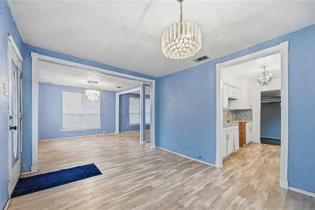 a view of empty room with wooden floor and kitchen view