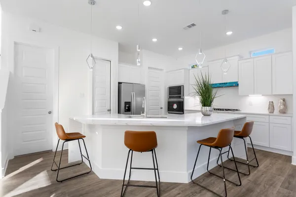 a kitchen with stainless steel appliances granite countertop a refrigerator and a wooden floor