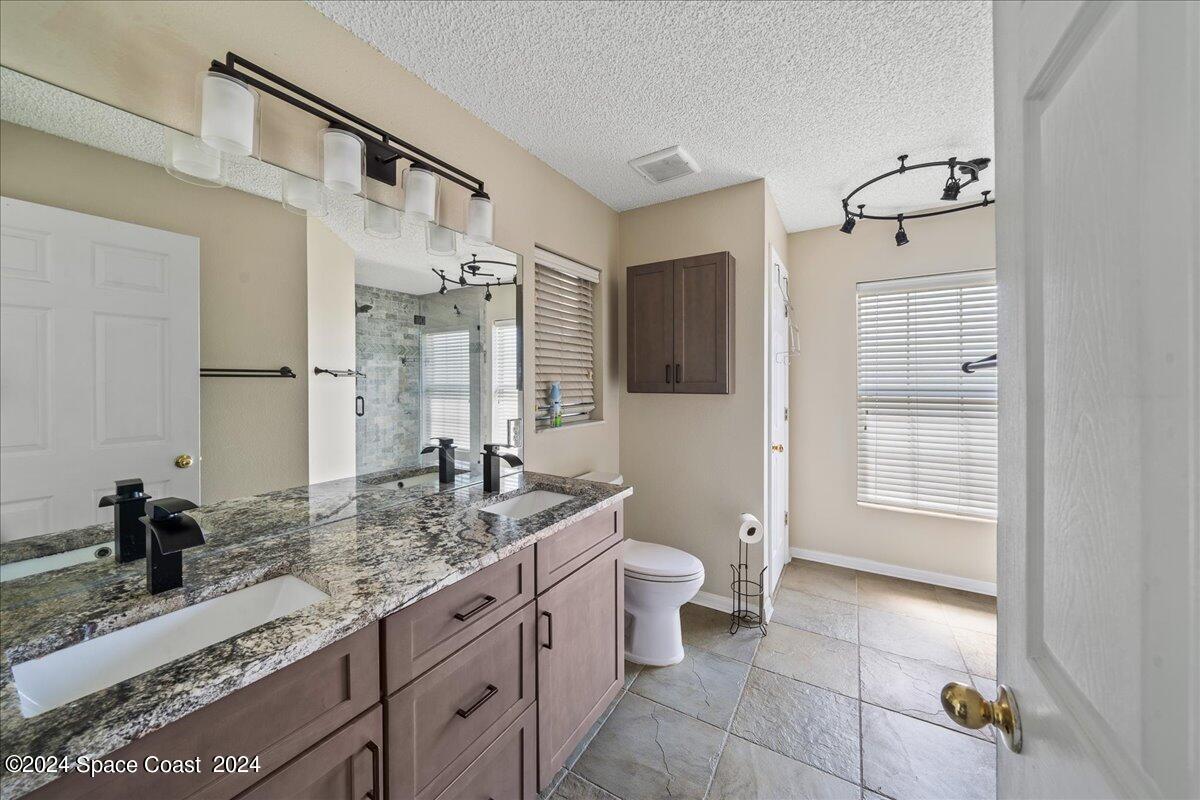 4850 Decatur Circle Melbourne, FL 32934 - Photo 17 of 35 a bathroom with a granite countertop sink a toilet and shower