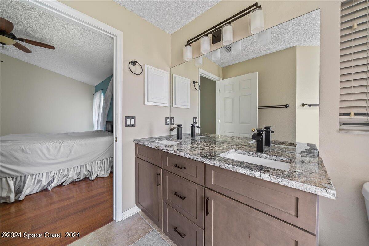 4850 Decatur Circle Melbourne, FL 32934 - Photo 18 of 35 a bathroom with a granite countertop sink a mirror and a shower