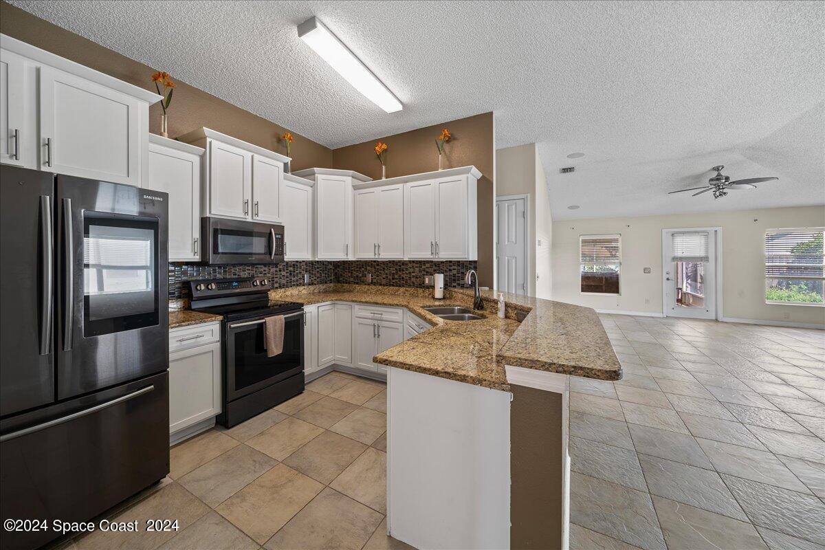 4850 Decatur Circle Melbourne, FL 32934 - Photo 6 of 35 a kitchen with stainless steel appliances granite countertop a sink stove and refrigerator