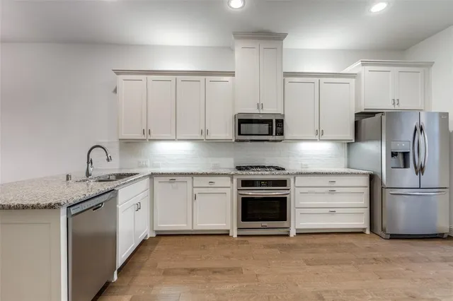 a kitchen with cabinets stainless steel appliances and a sink