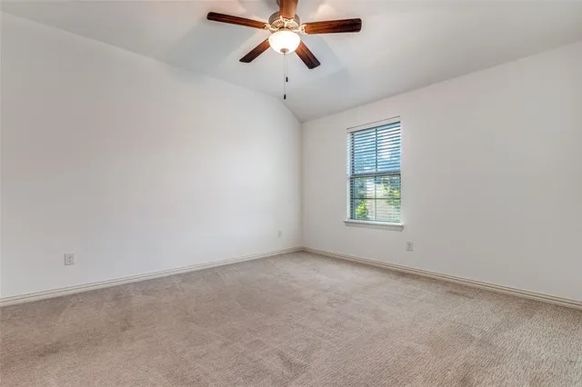 an empty room with chandelier fan and windows