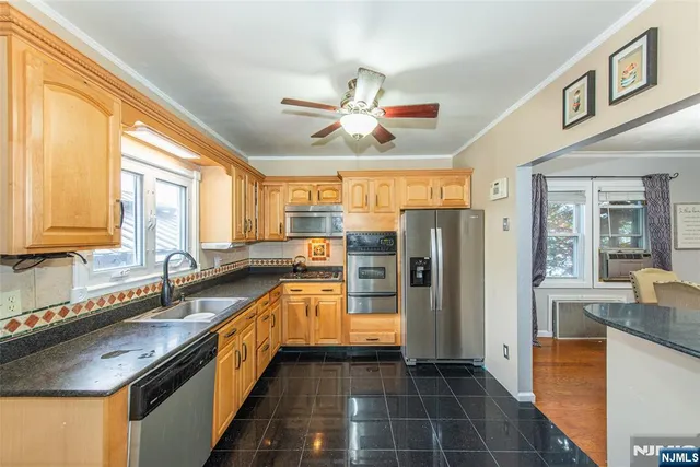 a kitchen with stainless steel appliances granite countertop a sink and a refrigerator