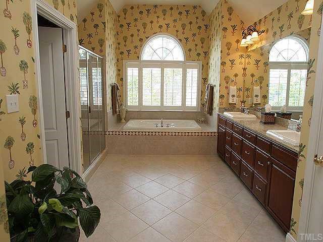 9508 Bluemont Court Raleigh, NC 27617 - Photo 8 of 10 a spacious bathroom with a sink a mirror and a bathtub next to a window