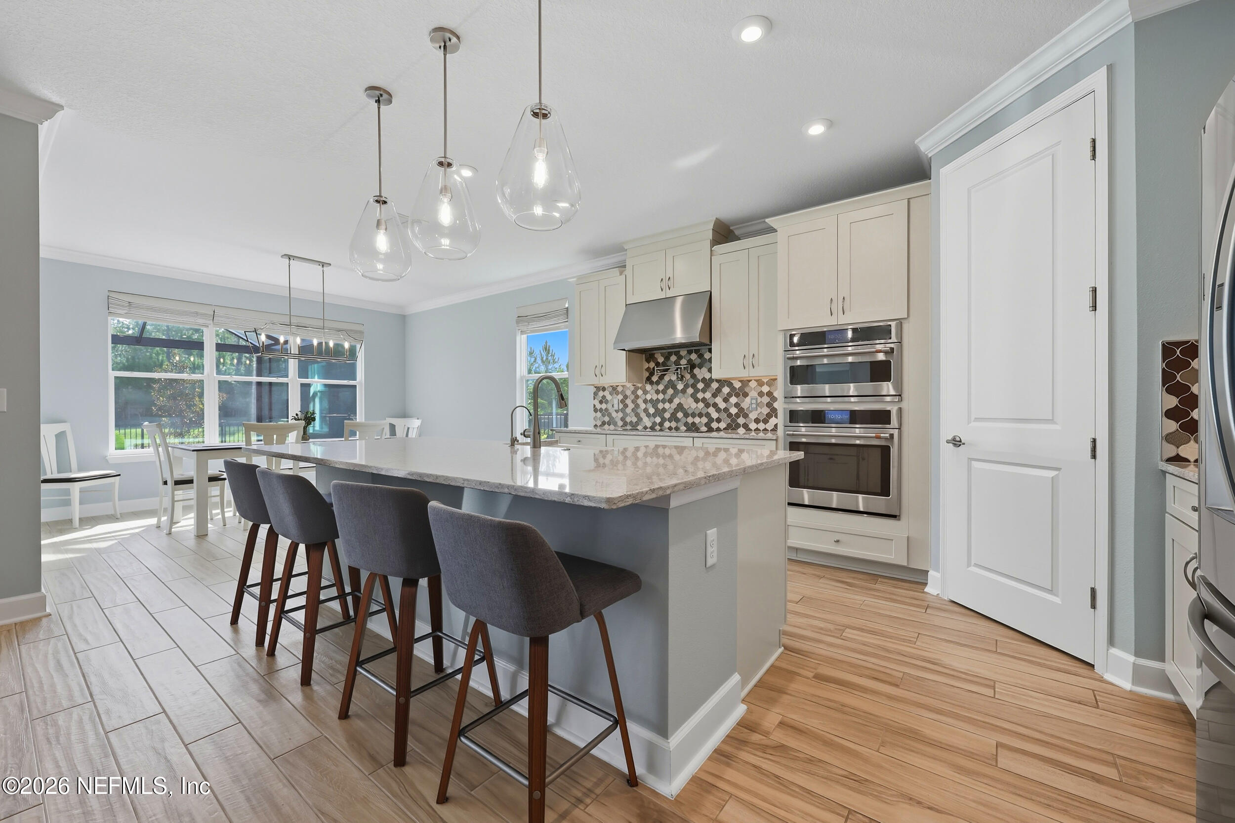 494 Marquesa Circle St. Johns, FL 32259 - Photo 16 of 76 a kitchen with kitchen island granite countertop a table chairs a sink dishwasher refrigerator and cabinets with wooden floor