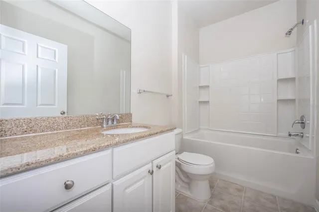 a bathroom with a granite countertop sink a toilet and shower