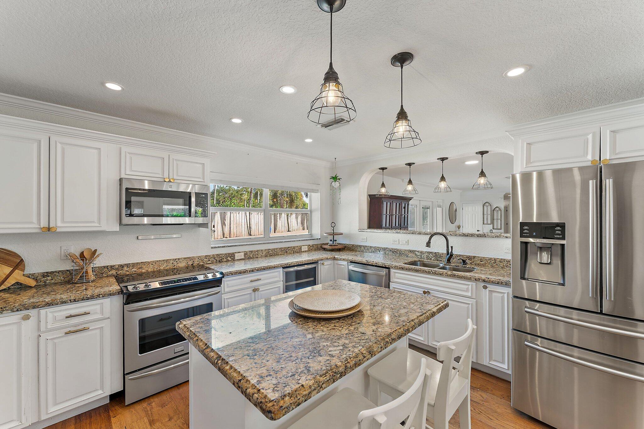 5692 Pennock Point Road Jupiter, FL 33458 - Photo 16 of 51 a kitchen with stainless steel appliances granite countertop a stove a sink a microwave a refrigerator and white cabinets