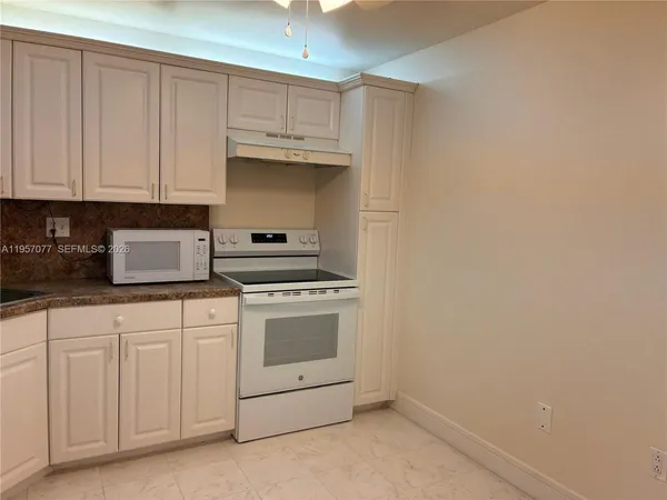 a kitchen with granite countertop white cabinets and white appliances