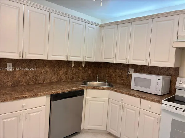 a kitchen with stainless steel appliances granite countertop white cabinets sink and dishwasher