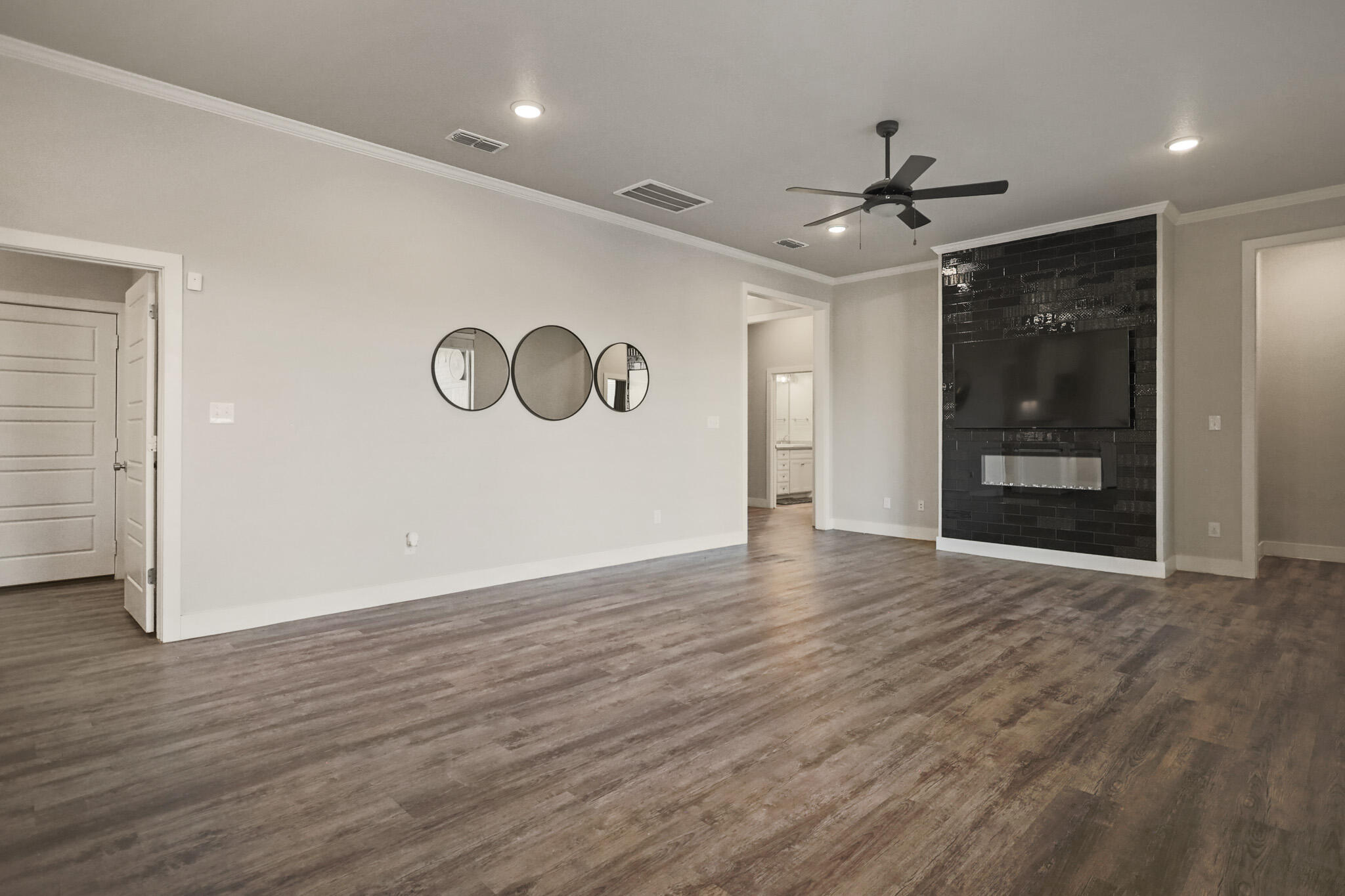 7808 58th Street Lubbock, TX 79407 - Photo 7 of 50 a view of an empty room with wooden floor and a ceiling fan