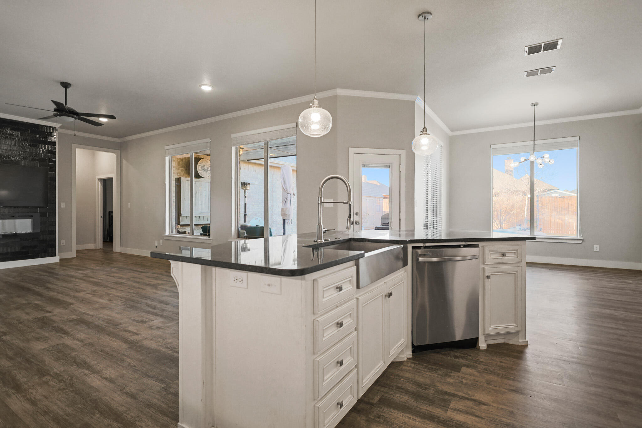 7808 58th Street Lubbock, TX 79407 - Photo 9 of 50 a large kitchen with granite countertop a large kitchen island white cabinetry and wooden floor