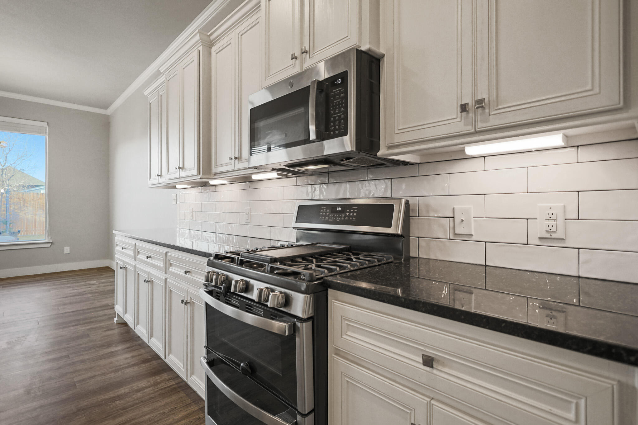 7808 58th Street Lubbock, TX 79407 - Photo 10 of 50 a kitchen with stainless steel appliances granite countertop a stove and a microwave