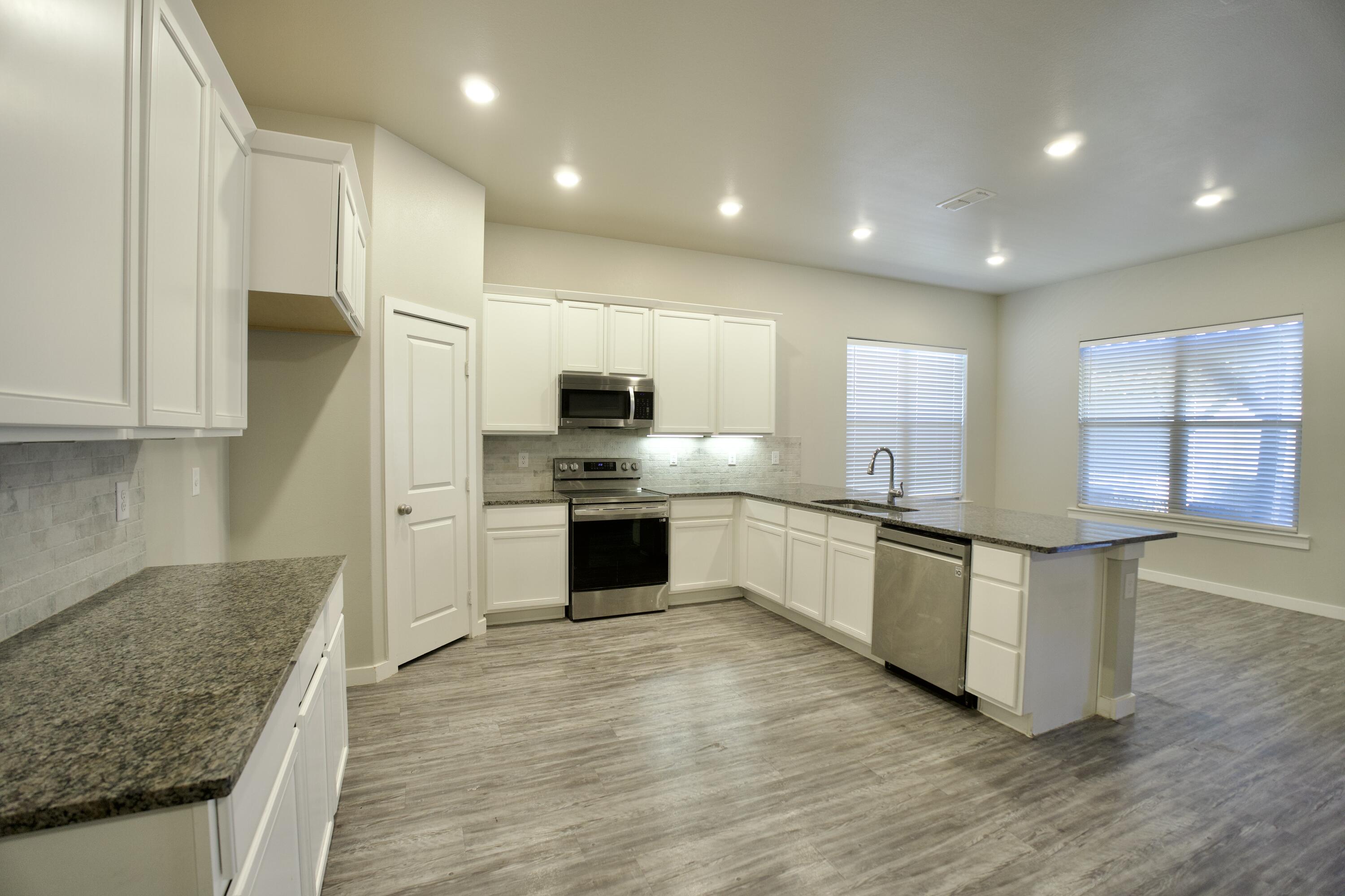 1604 137th Street Lubbock, TX 79423 - Photo 6 of 19 a white kitchen with stainless steel appliances granite countertop a stove and a sink