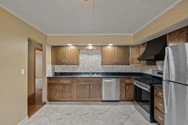 a kitchen with stainless steel appliances granite countertop a stove a sink and a refrigerator