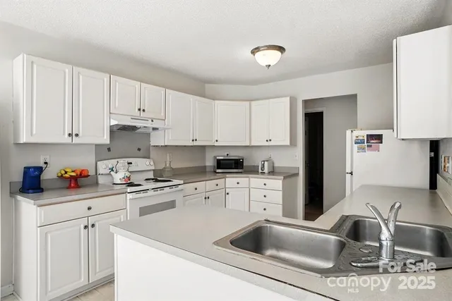 a kitchen with granite countertop a sink dishwasher a stove and white cabinets