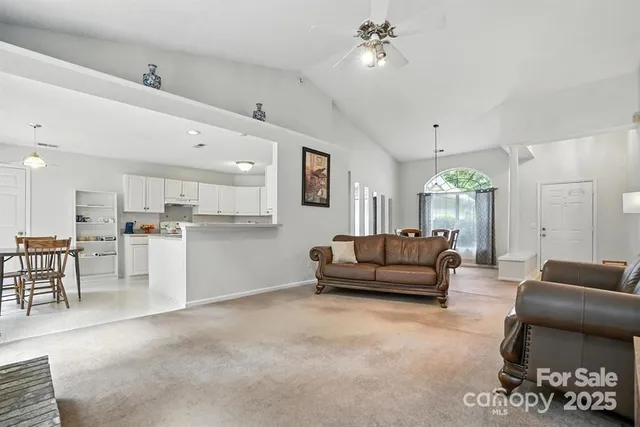 a living room with furniture and a dining table with kitchen view