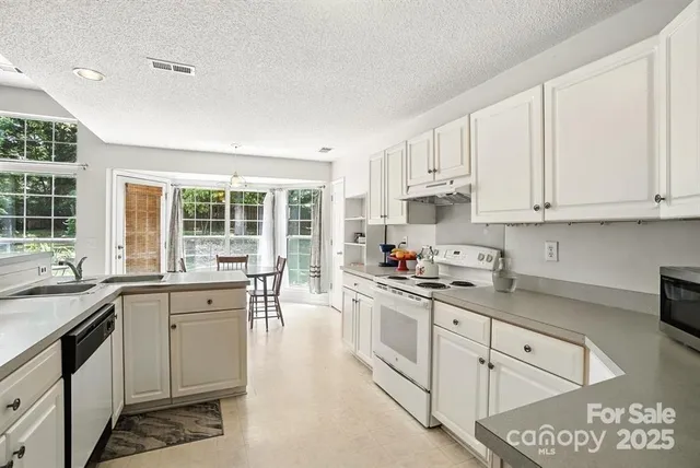 a kitchen with granite countertop white cabinets and white appliances