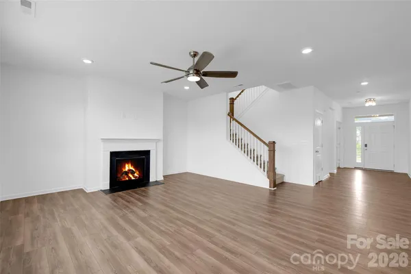 a view of an empty room with wooden floor a fireplace and a window