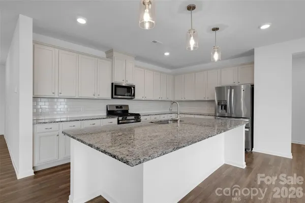 a kitchen with stainless steel appliances granite countertop a sink a stove and a refrigerator