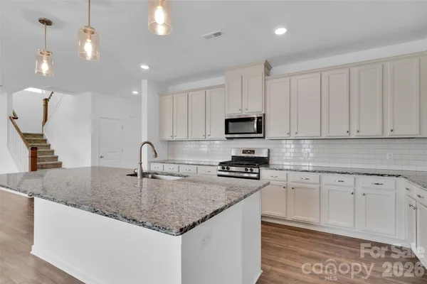 a kitchen with stainless steel appliances granite countertop a sink a stove microwave and cabinets