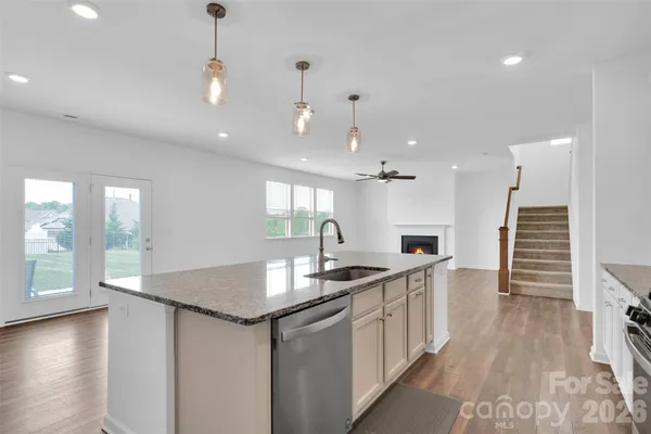 a kitchen with stainless steel appliances granite countertop a sink a stove and a wooden floors