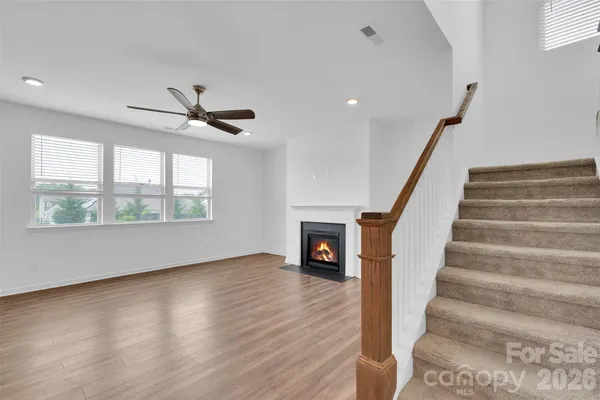 a view of an empty room with wooden floor a ceiling fan and windows