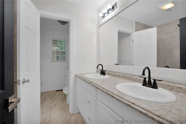 a bathroom with double vanity sinks and a mirror