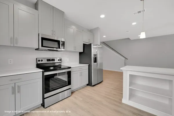 a kitchen with cabinets stainless steel appliances and wooden floor